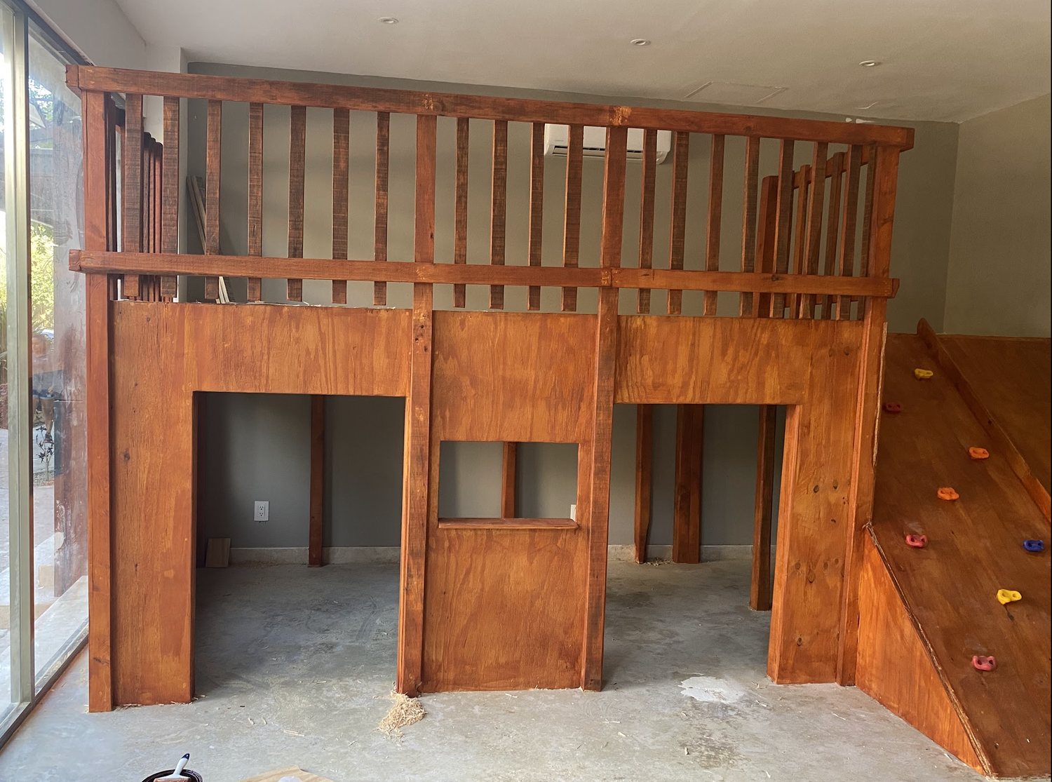 Finished hardwood children's loft with climbing wall built in a Tulum home